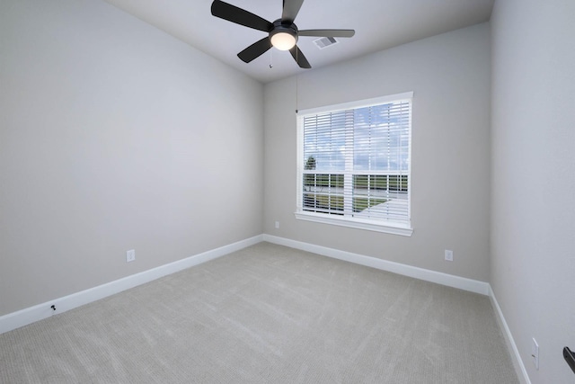 unfurnished room featuring baseboards, visible vents, light colored carpet, and ceiling fan