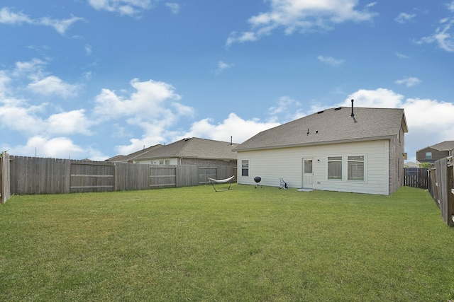 rear view of house with a fenced backyard and a yard