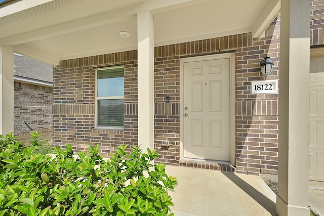 entrance to property featuring brick siding and a porch