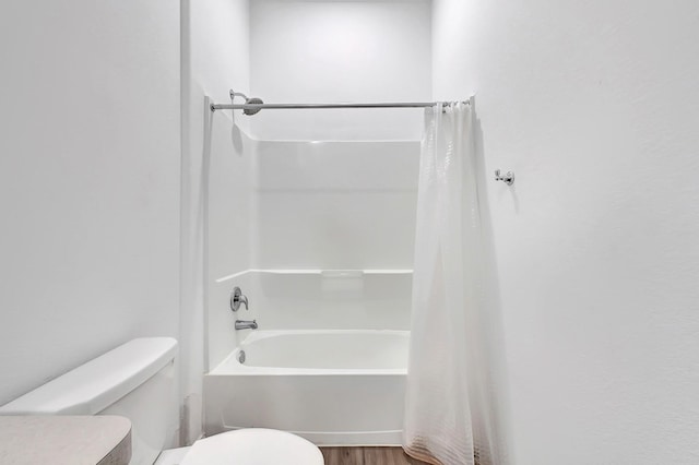 bathroom with wood finished floors, toilet, and shower / bath combination with curtain