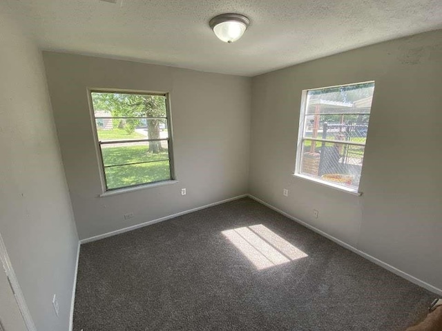 spare room with carpet floors, a textured ceiling, and baseboards