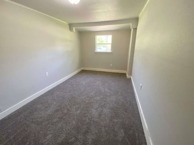 unfurnished room with baseboards and dark carpet