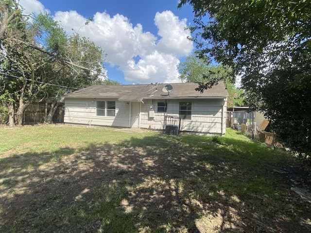 rear view of property featuring fence and a yard