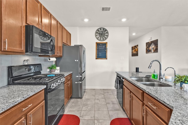 kitchen featuring light stone counters, visible vents, a sink, baseboards, and black appliances