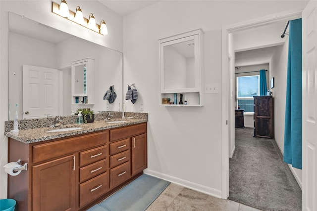 bathroom with baseboards, a sink, and double vanity