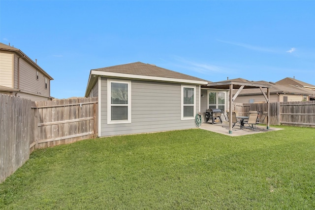 rear view of property featuring a yard, a patio, and a fenced backyard