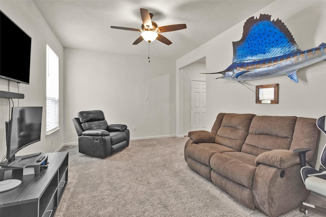 carpeted living room featuring baseboards, a ceiling fan, and plenty of natural light