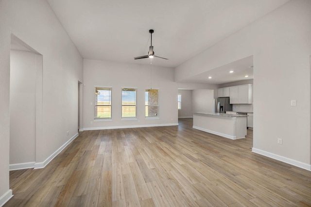 unfurnished living room featuring baseboards, ceiling fan, and light wood-type flooring