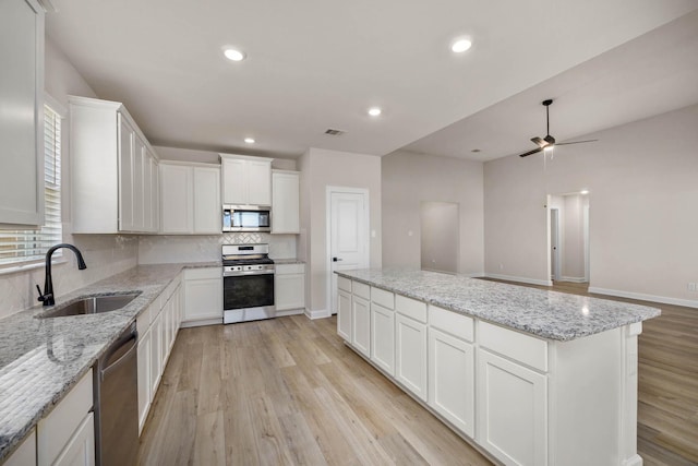 kitchen featuring a ceiling fan, tasteful backsplash, light wood-type flooring, a sink, and stainless steel appliances