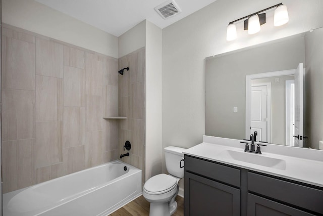 full bath with visible vents, wood finished floors, vanity, toilet, and washtub / shower combination