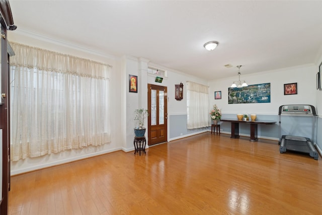 interior space with wood finished floors, ornamental molding, baseboards, and a notable chandelier