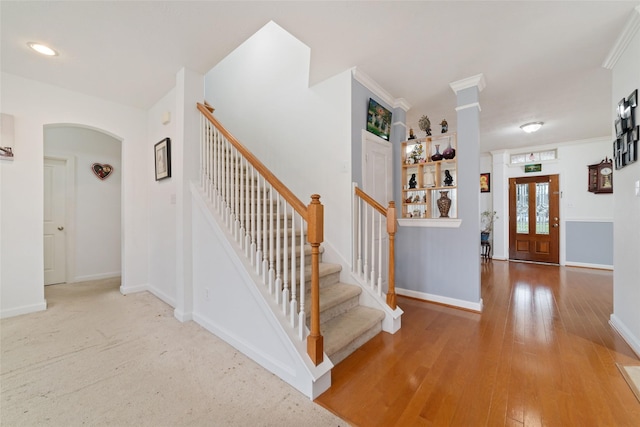 entrance foyer featuring arched walkways, baseboards, wood-type flooring, and stairs