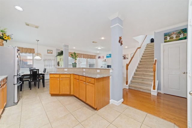 kitchen featuring light stone counters, light tile patterned floors, pendant lighting, visible vents, and freestanding refrigerator