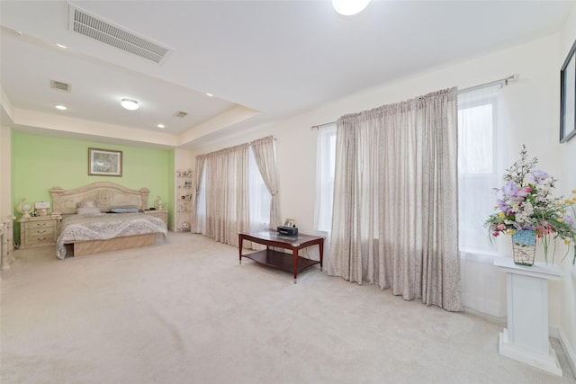 bedroom with a tray ceiling, carpet, and visible vents