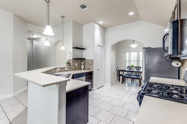 kitchen featuring stainless steel appliances, a peninsula, arched walkways, a sink, and light countertops