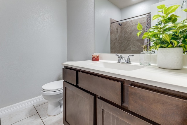 bathroom featuring toilet, vanity, baseboards, tile patterned flooring, and tiled shower