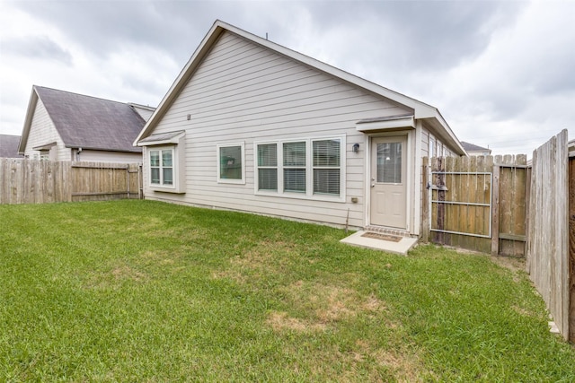 back of house featuring a lawn and a fenced backyard
