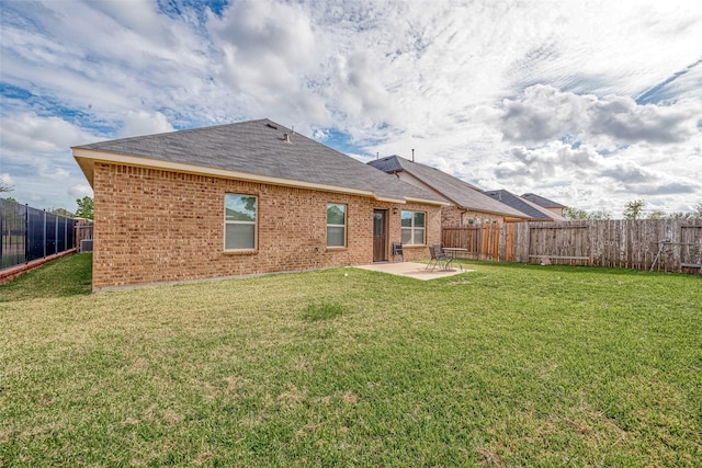 rear view of house featuring a fenced backyard, a yard, a patio area, and brick siding