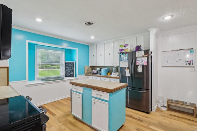 9 Slover Dr, Dayton, TX 77535 - kitchen featuring tile counters, freestanding refrigerator, white cabinetry, and crown molding