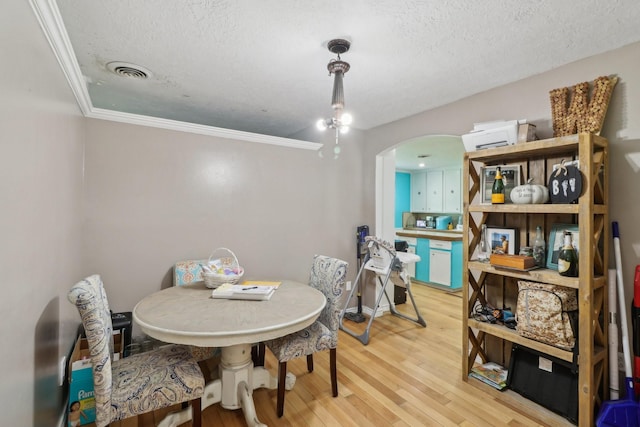 9 Slover Dr, Dayton, TX 77535 - dining room with crown molding, a textured ceiling, arched walkways, light wood-style flooring, and visible vents