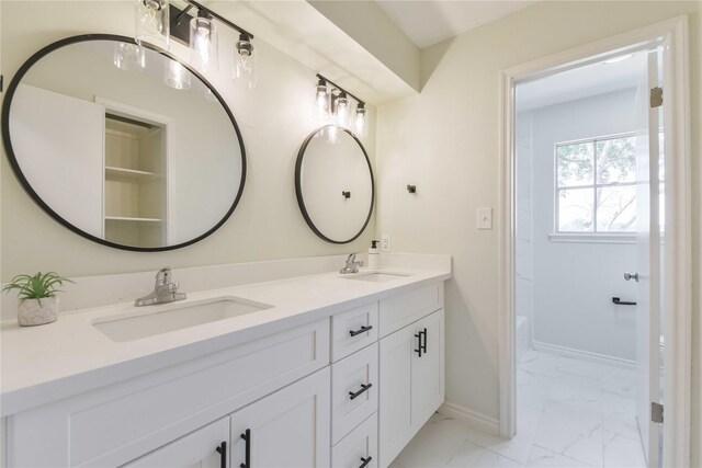 bathroom with baseboards, marble finish floor, a sink, and double vanity