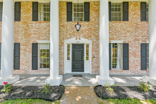 entrance to property with brick siding and a porch