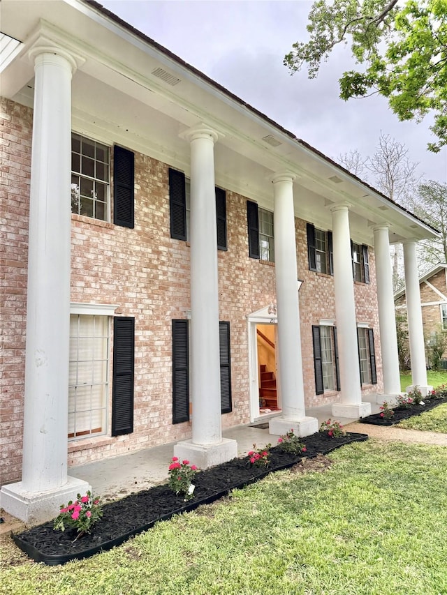 exterior space with brick siding, a front yard, and covered porch