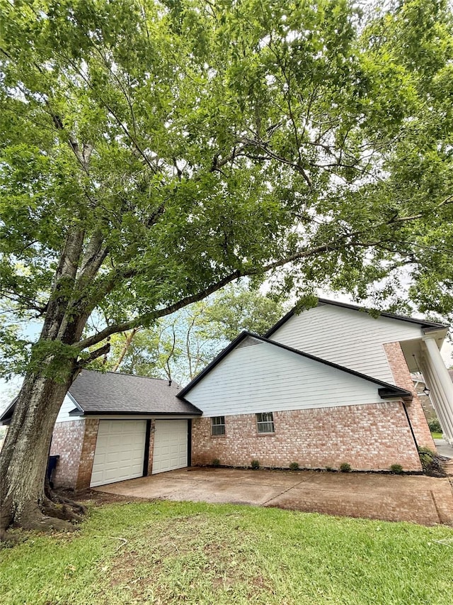 view of property exterior featuring brick siding, driveway, and a garage