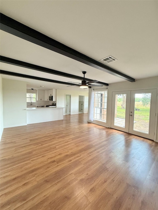 unfurnished living room featuring light wood finished floors, visible vents, french doors, beam ceiling, and ceiling fan