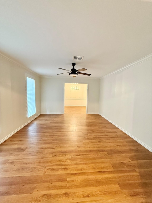 empty room with baseboards, visible vents, light wood-style floors, ceiling fan, and ornamental molding