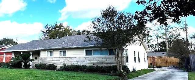 exterior space with a lawn, a gate, stone siding, and concrete driveway
