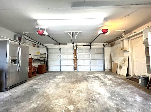 garage with a garage door opener and stainless steel fridge with ice dispenser