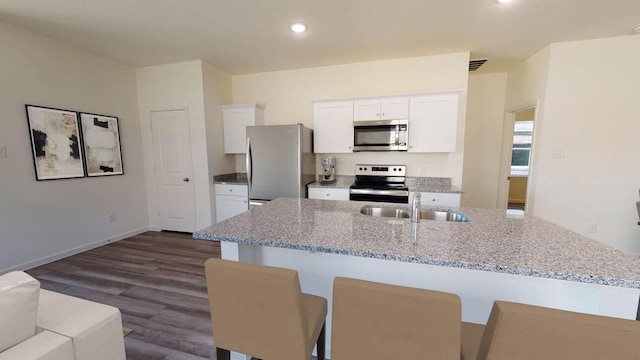 kitchen with dark wood-style floors, white cabinetry, a center island with sink, appliances with stainless steel finishes, and a sink