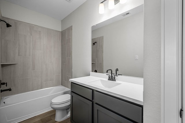 bathroom with visible vents, toilet, shower / bath combination, wood finished floors, and vanity