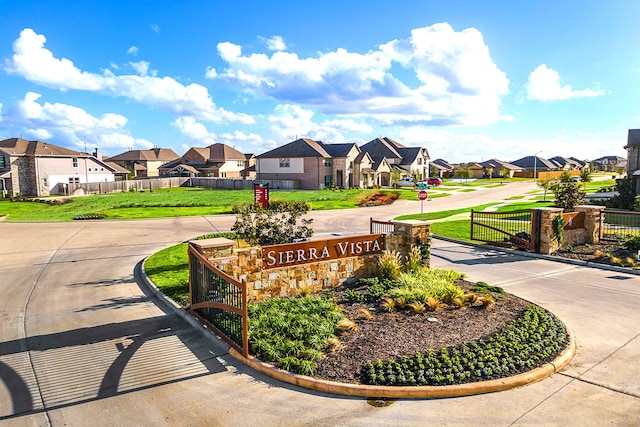 view of community featuring fence, a lawn, and a residential view
