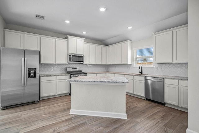 kitchen with stainless steel appliances, visible vents, backsplash, and light wood-style flooring