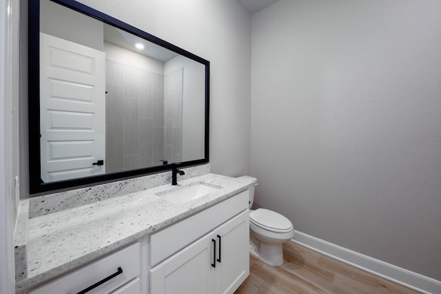 bathroom featuring baseboards, wood finished floors, toilet, and vanity