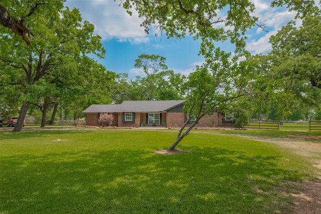 ranch-style house featuring brick siding, a front lawn, and fence