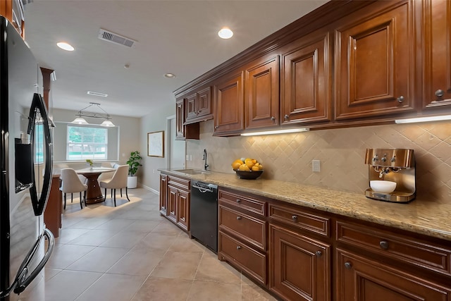 kitchen with a sink, stainless steel fridge, backsplash, black dishwasher, and visible vents