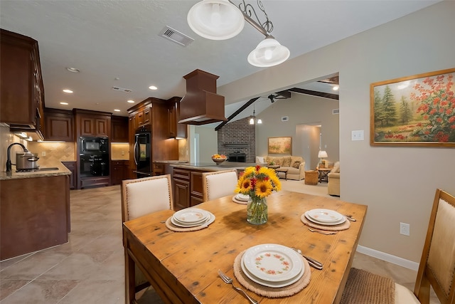 dining space with vaulted ceiling, visible vents, a fireplace, and ceiling fan