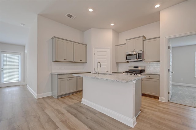 kitchen with visible vents, stainless steel appliances, gray cabinetry, and backsplash