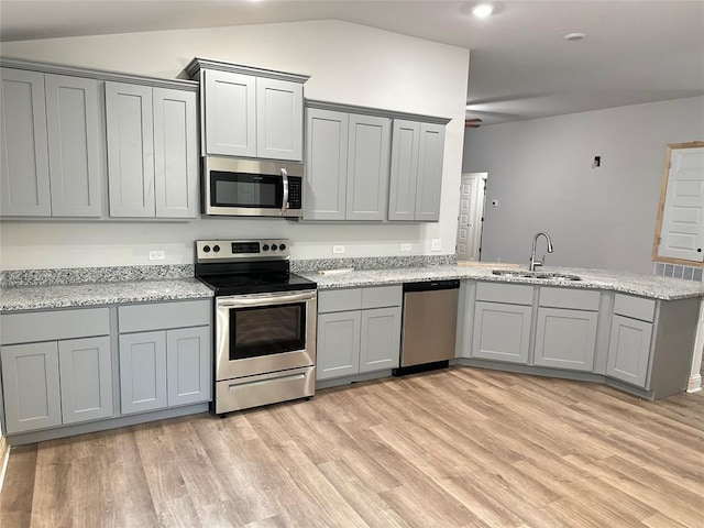 kitchen featuring gray cabinets, a peninsula, appliances with stainless steel finishes, and a sink
