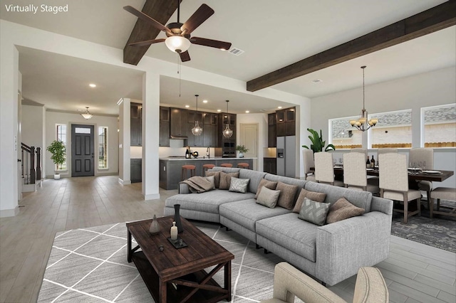 1310 Layla Sage Loop, Richmond, TX 77406 - living area with light wood-style floors, visible vents, beamed ceiling, and ceiling fan with notable chandelier