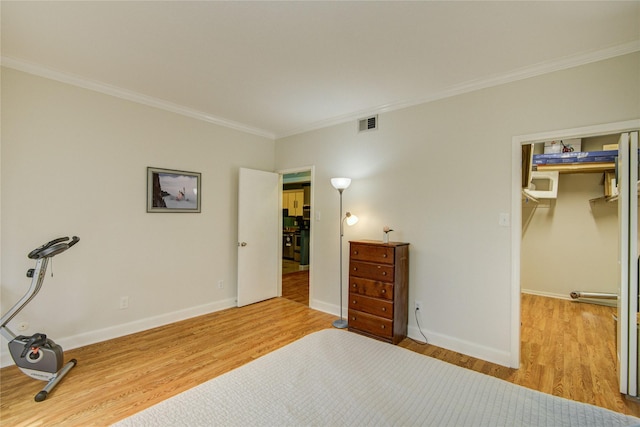 bedroom with baseboards, ornamental molding, wood finished floors, and visible vents