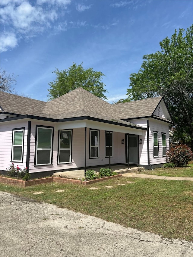 view of front of home featuring a porch, a front lawn, and roof with shingles