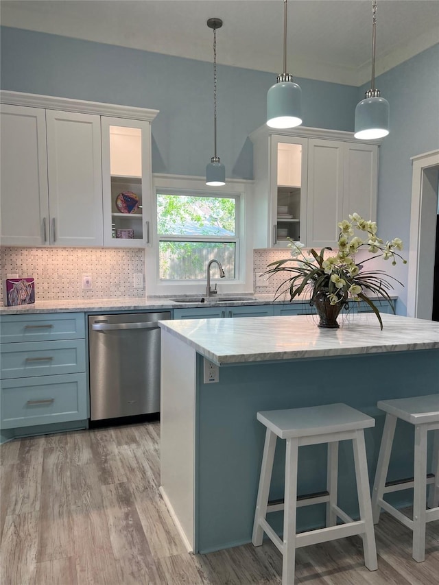 kitchen featuring light wood finished floors, a sink, tasteful backsplash, dishwasher, and hanging light fixtures