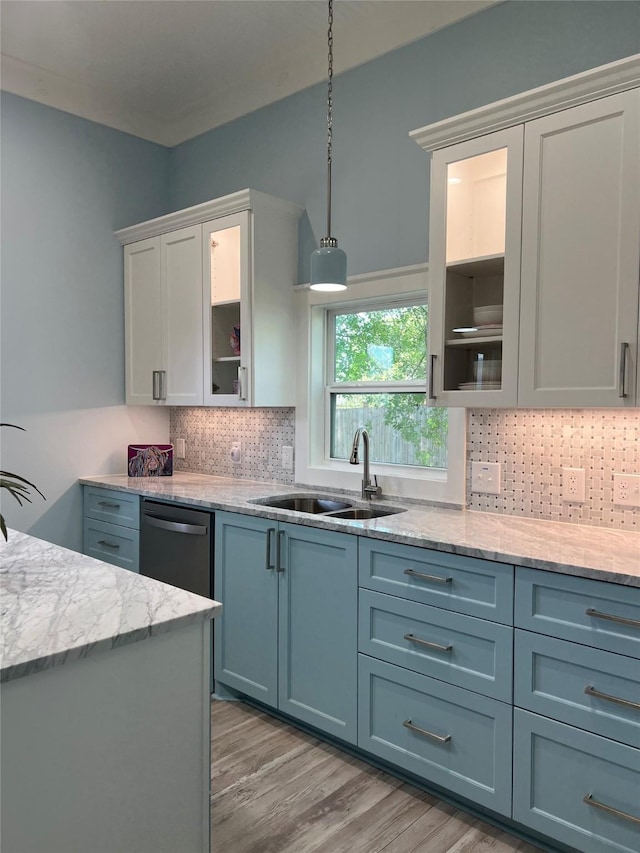 kitchen with backsplash, dishwashing machine, a sink, light wood-style floors, and glass insert cabinets
