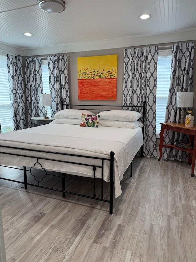 bedroom with ornamental molding, multiple windows, wood finished floors, and recessed lighting