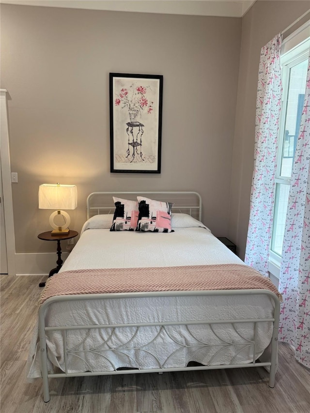 bedroom with wood finished floors and multiple windows