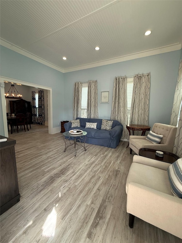 living area featuring wood finished floors, ornamental molding, baseboards, a notable chandelier, and recessed lighting
